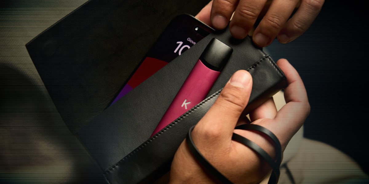 Kiwi Vape in Pink mit 10 mg Nikotin in schwarzer Tasche, Nahaufnahme mit Händen und Zubehör.
